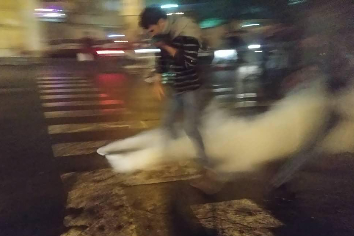 An Iranian protester covers his face to protect himself from tear gas during a demonstration against an increase in gasoline prices in the capital Tehran, on November 16, 2019. - One person was killed