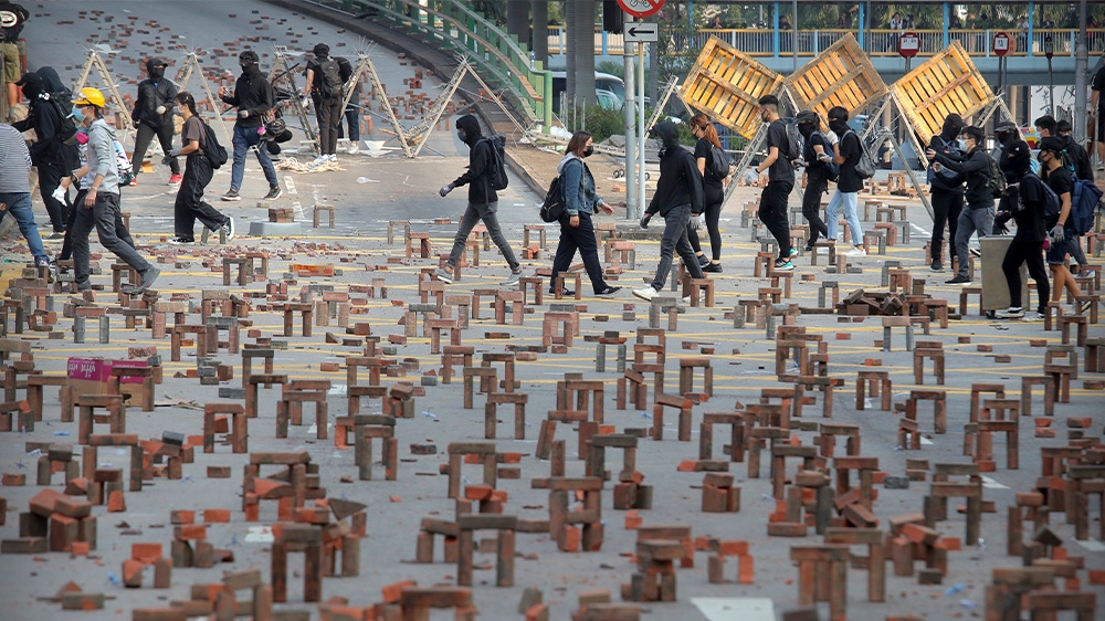 Protesters walk through barricades of bricks on a road near the Hong Kong Polytechnic University in Hong Kong. Protesters have sought to paralyse the city throughout the week.