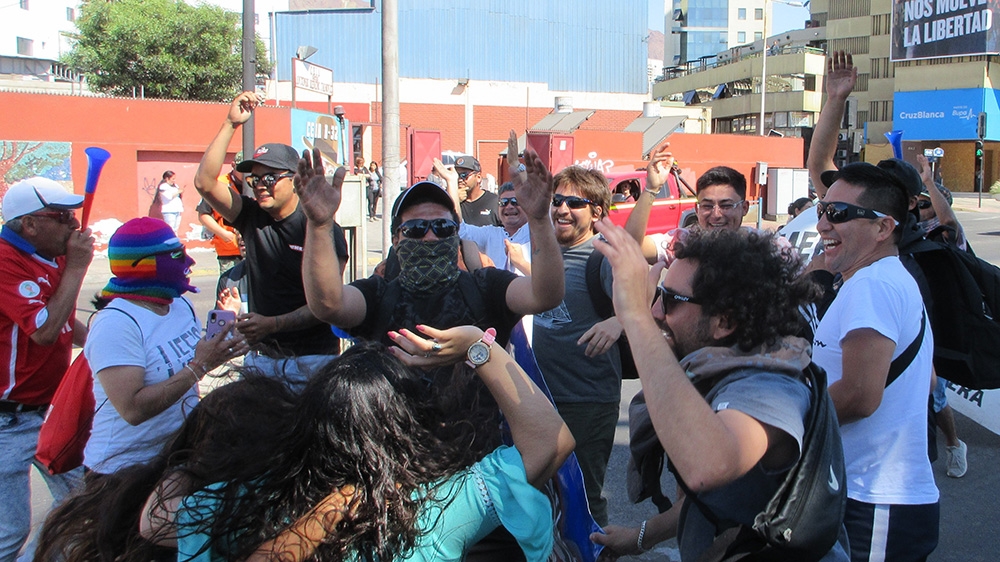 Striking dockworkers in Antofagasta block a major boulevard, allowing drivers to pass when they get out and dance