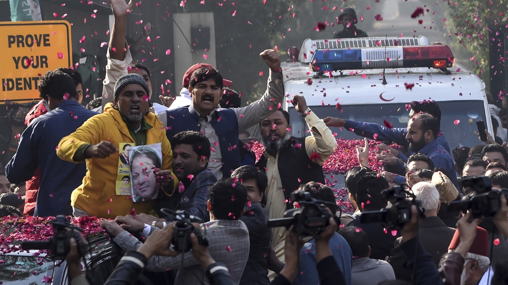 Supporters of Pakistan Muslim League Nawaz (PML-N) gather around a vehicle, covered with rose petals, carrying the ailing former Pakistani Prime Minister Nawaz Sharif