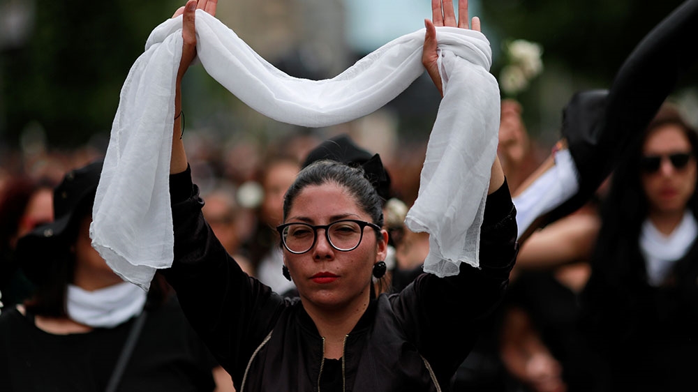 A woman rises up a white scarf as she takes part in a march to pay tribute to people killed during the protests against Chile’s government,