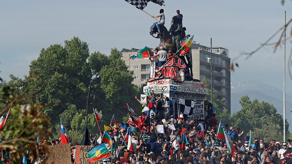 Demonstrators climb a statue during a protest against Chile’s government in Santiago, Chile