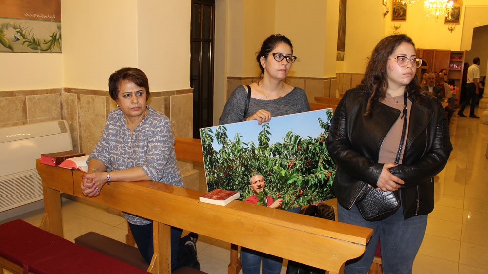 Noura Areed holding her husband’s picture in church following mass [Photo courtesy of Arbeed family]