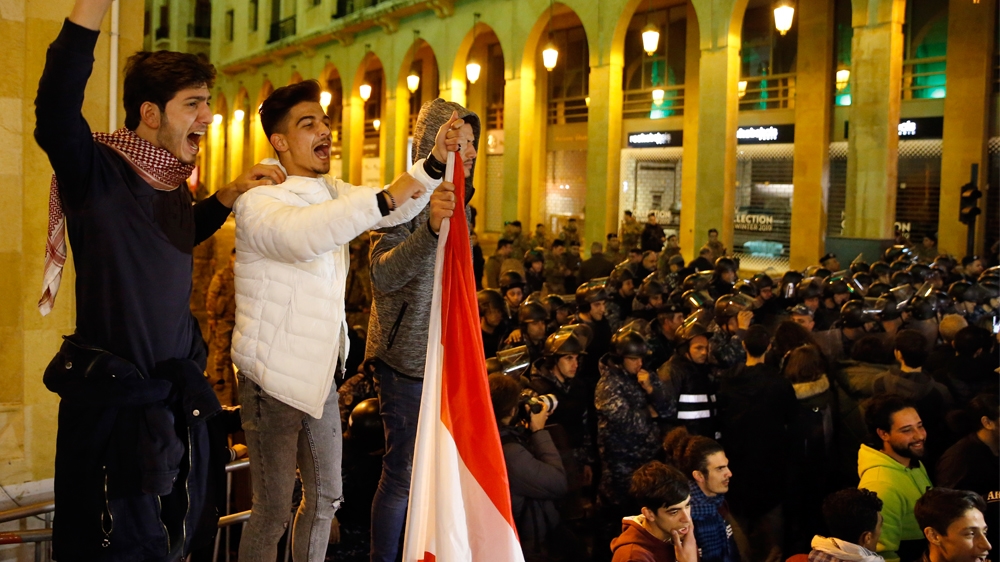 Protesters chant slogans during ongoing protests against the Lebanese political class, as riot police block a road leading to the parliament building in Beirut, Lebanon, Sunday, Dec. 8, 2019.