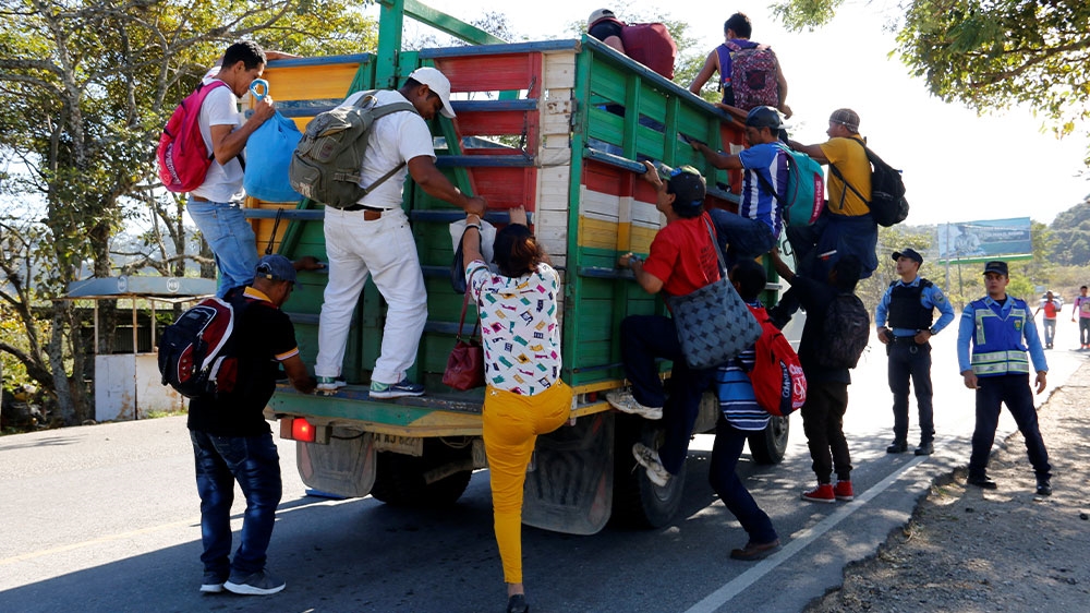 Honduran migrants climb on a truck as they head towards the United States as part of a new caravan of migrants, in Cucuyagua, Honduras [Reuters]