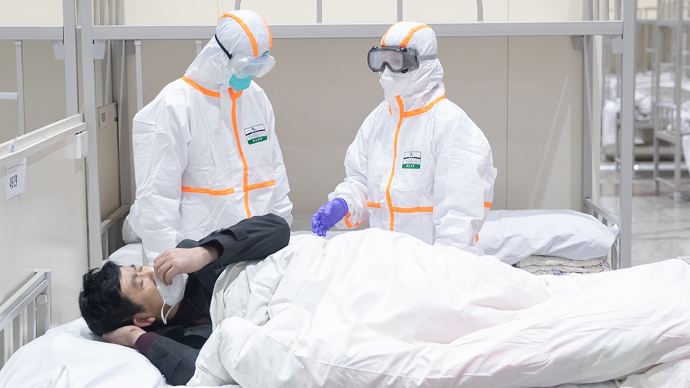 epa08196535 Medical staff attend to a patient infected by the coronavirus at a makeshift hospital at Wuhan International Convention and Exhibition Center in Wuhan City, Hubei Province, China, 05 Febru