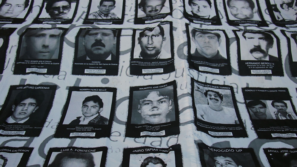 Protesters hold a sign outside the JEP with the photos of some of the victims of the false positives scandal