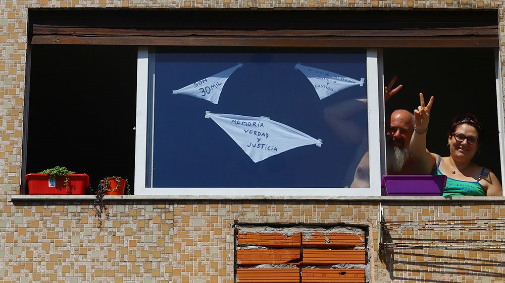 A man and a woman are seen with white handkerchiefs on their windows, symbols of the National Day of Remembrance for Truth and Justice