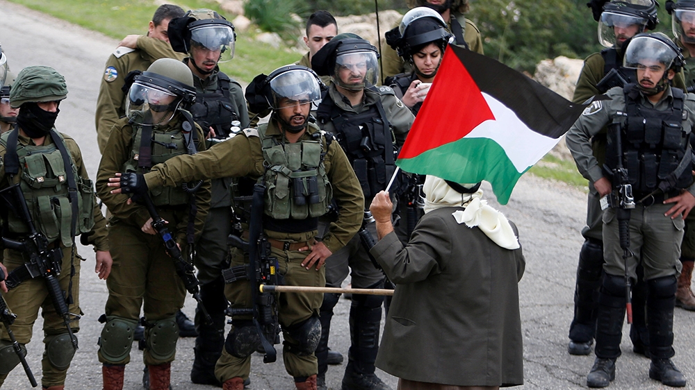 A demonstrator holding a Palestinian flag stands in front of Israeli forces during a protest against Israeli settlements and the U.S. President Donald Trump''s Middle East peace plan, in Jordan Valley