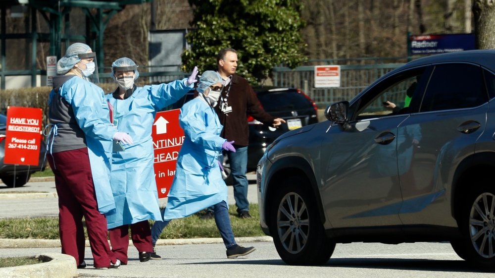 Healthcare workers direct a car at a COVID-19 temporary testing site near Penn Medicine Radnor, Pennsylvania, in March 2020