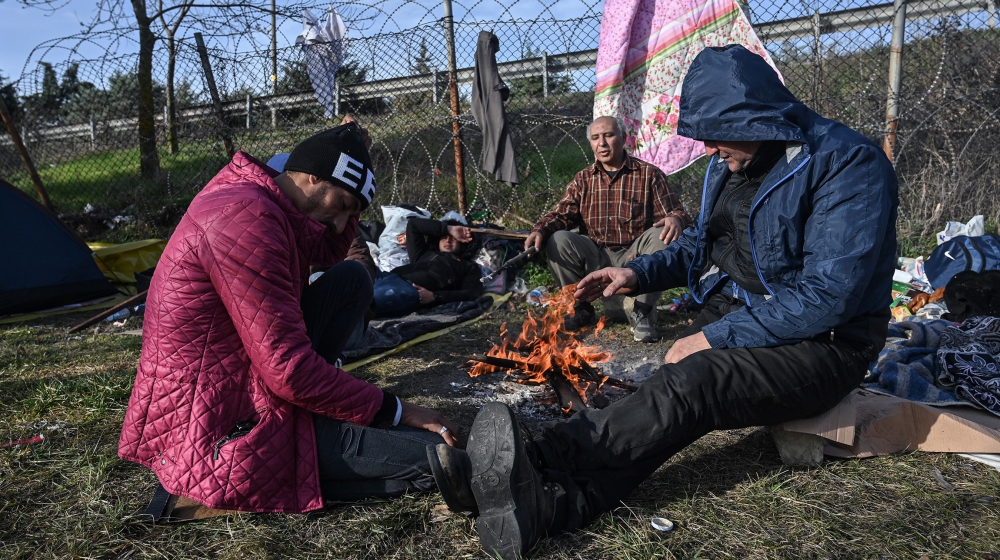 Migrants sit around a fire as they gather near a bus terminal waiting to resume their efforts to enter Europe near Pazarkule border gate in the city of Edirne, northwest Turkey on March 8, 2020. EU me