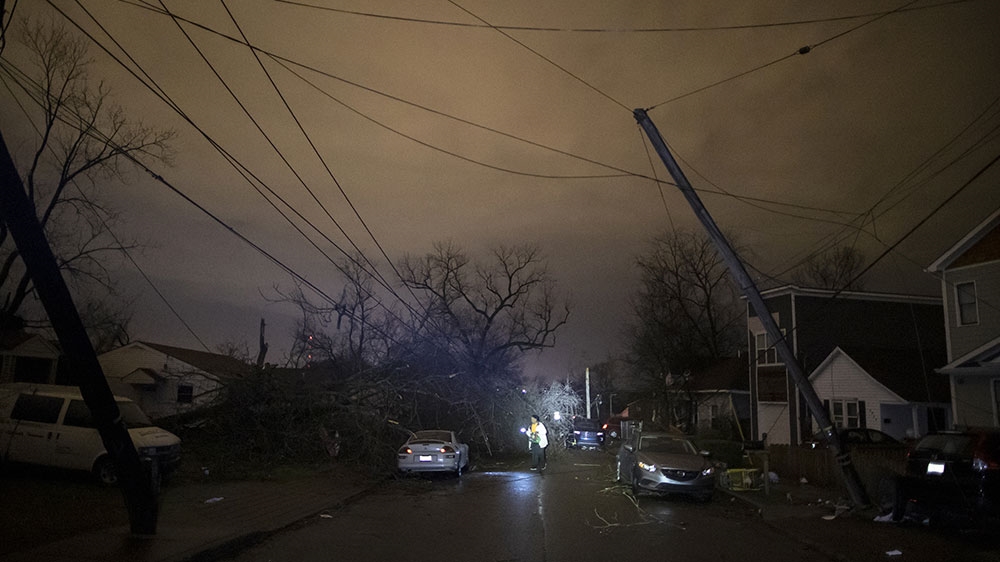 A resident makes her way down a street amid downed trees and heavy debris in Nashville, Tennessee