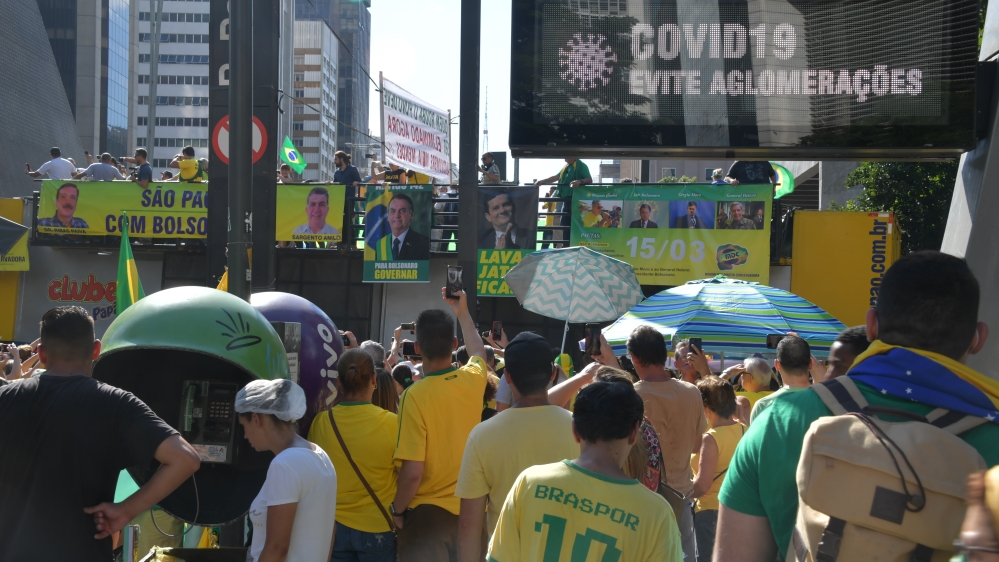 Supporters of Brazilian President Bolsonaro take part in a protest on Sunday in Sao Paulo near a public sign that reads ‘COVID-19 – Avoid crowds’