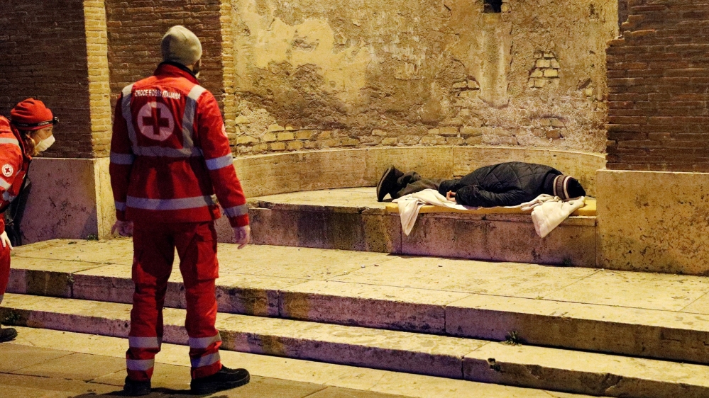 Red Cross workers check on a homeless person in Rome on Tuesday; Italy is on track to surpass China in the number of coronavirus-related deaths by March 19