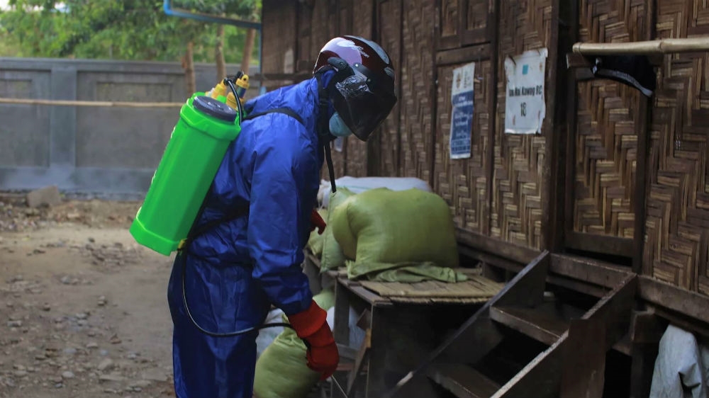 A volunteer from the Kachin State Covid-19 Prevention network sprays disinfectant in an IDP camp in Myitkyina, Kachin State [Al Jazeera]