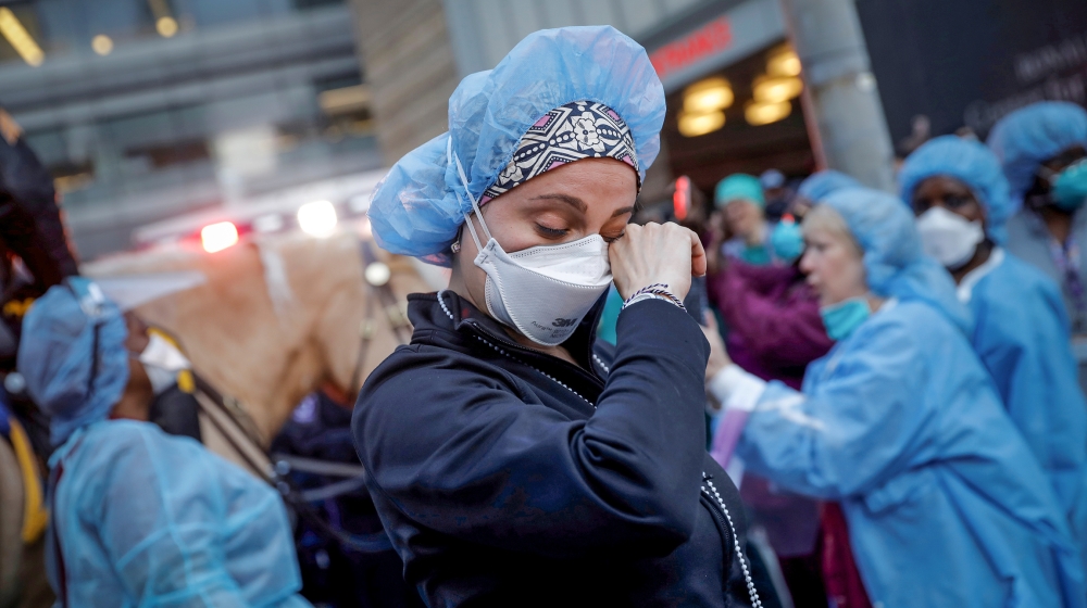 A nurse wipes away tears as she stands outside NYU Langone Medical Center on 1st Avenue in Manhattan as New York Police Department (NYPD) Mounted Police and other units came to cheer and thank healthc
