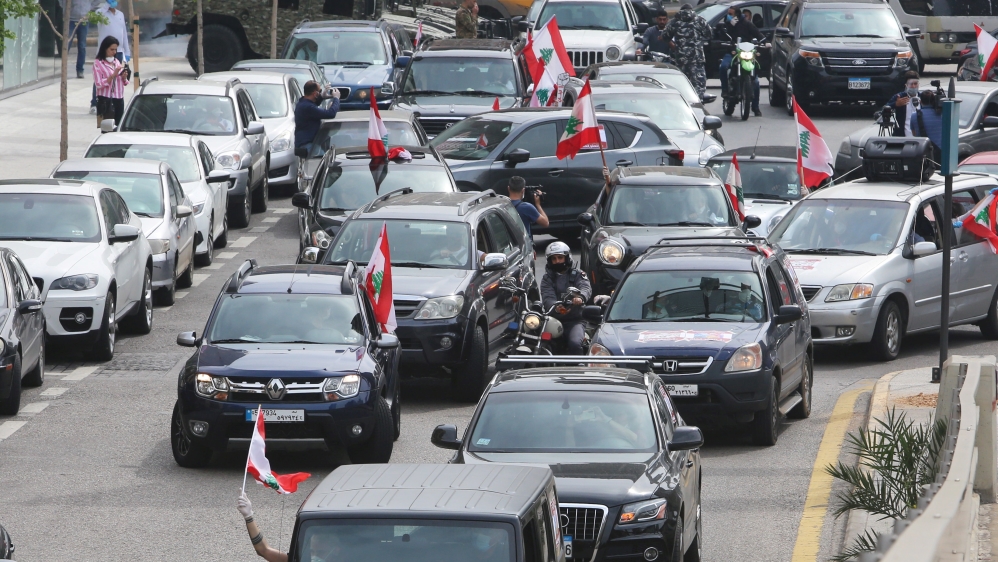 Anti-government demonstrators hold Lebanese flags as they protest in their cars, during a countrywide lockdown to combat the spread of the coronavirus disease (COVID-19), in Beirut