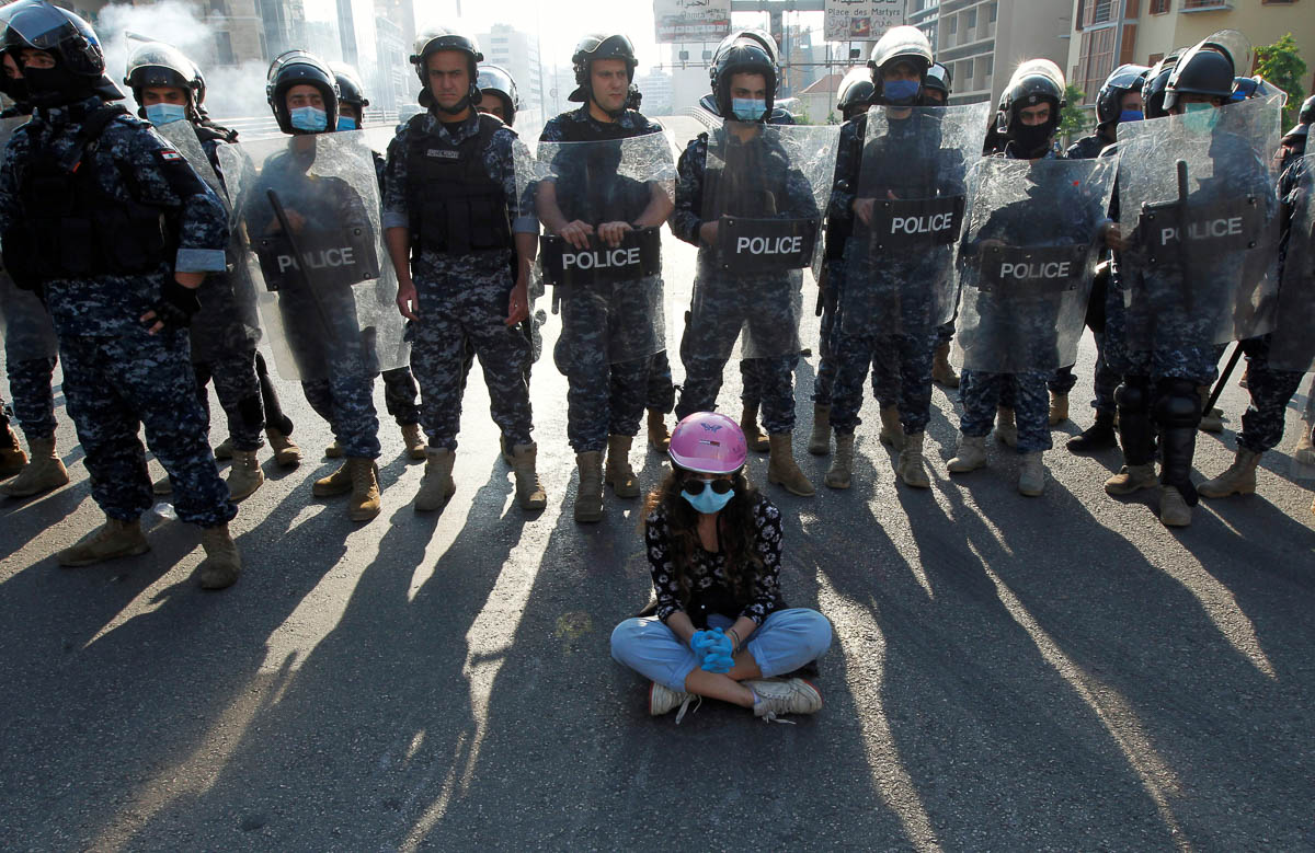 A demonstrator sits on the ground in front of Lebanese police officers during a protest against growing economic hardship in Beirut, Lebanon April 28, 2020. REUTERS/Mohamed Azakir