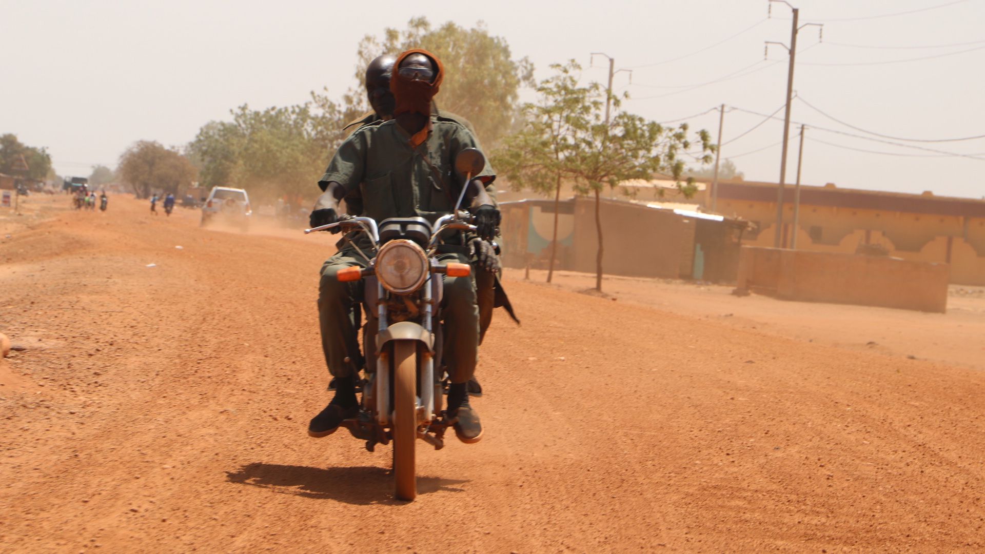 Two men from a self-defence militia group ride a motorbike outside the city of Boulsa