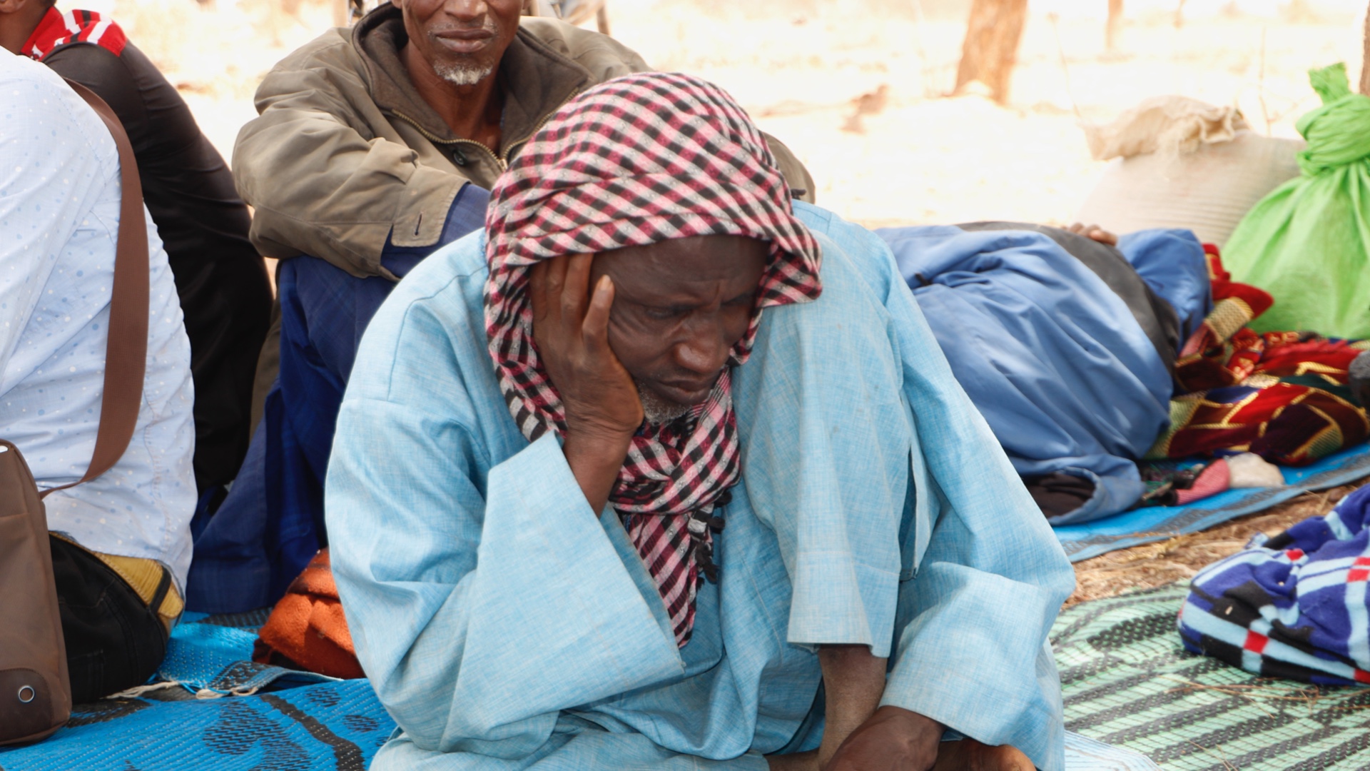 A man sits on the ground in a makeshift displacement site in Yatenga province. Days earlier he was forced to flee his home when gunmen attacked his village