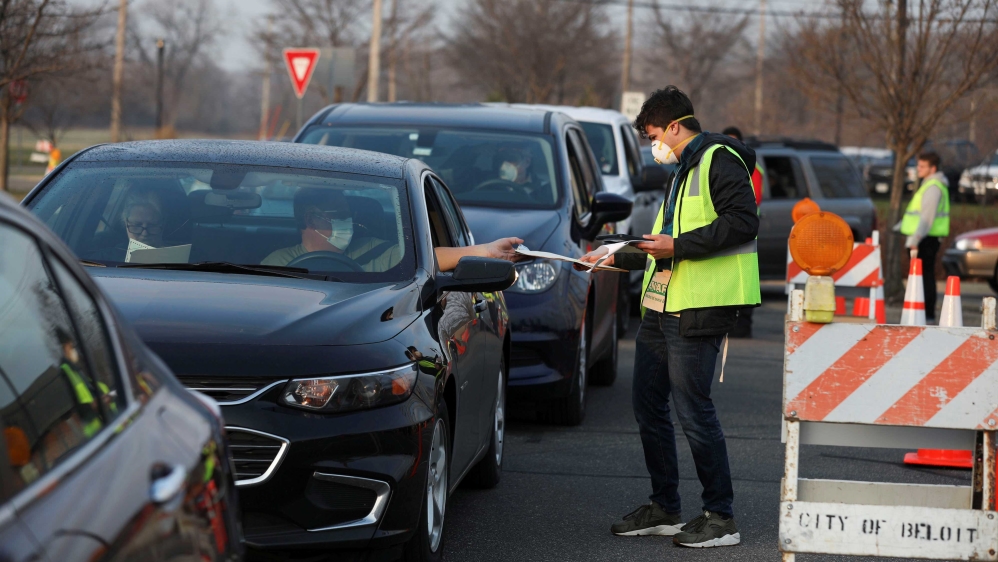 An election volunteer collecting a completed ballot from a voter after the city of Beloit consolidated all its precincts in a single drive-up location outside city hall for voters to cast ballots from their vehicles in Beloit, Wisconsin