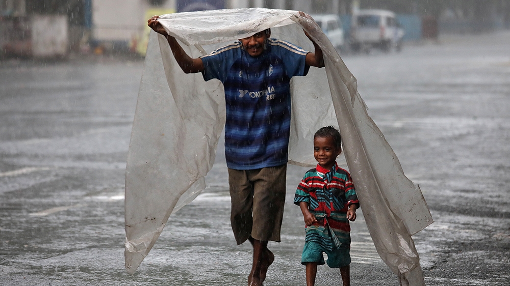 A homeless man and his son protecting themselves from the rain with a plastic sheet as they walk to a shelter in Kolkata during a nationwide lockdown
