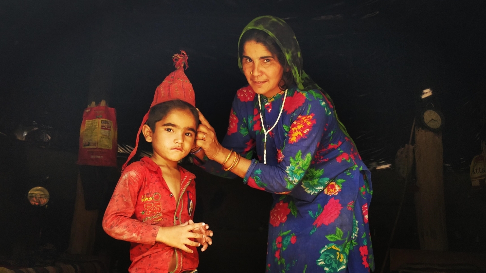Khadija places a traditional embroidered Van Gujjar cap on her son Yunus’s head