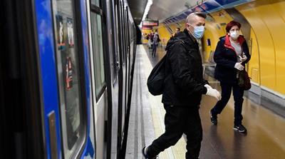 Commuters wearing face masks arrive at the Atocha Station in Madrid on April 13, 2020 as some companies were set to resume operations at the end of a two-weeks halt of all non-essential activity amid