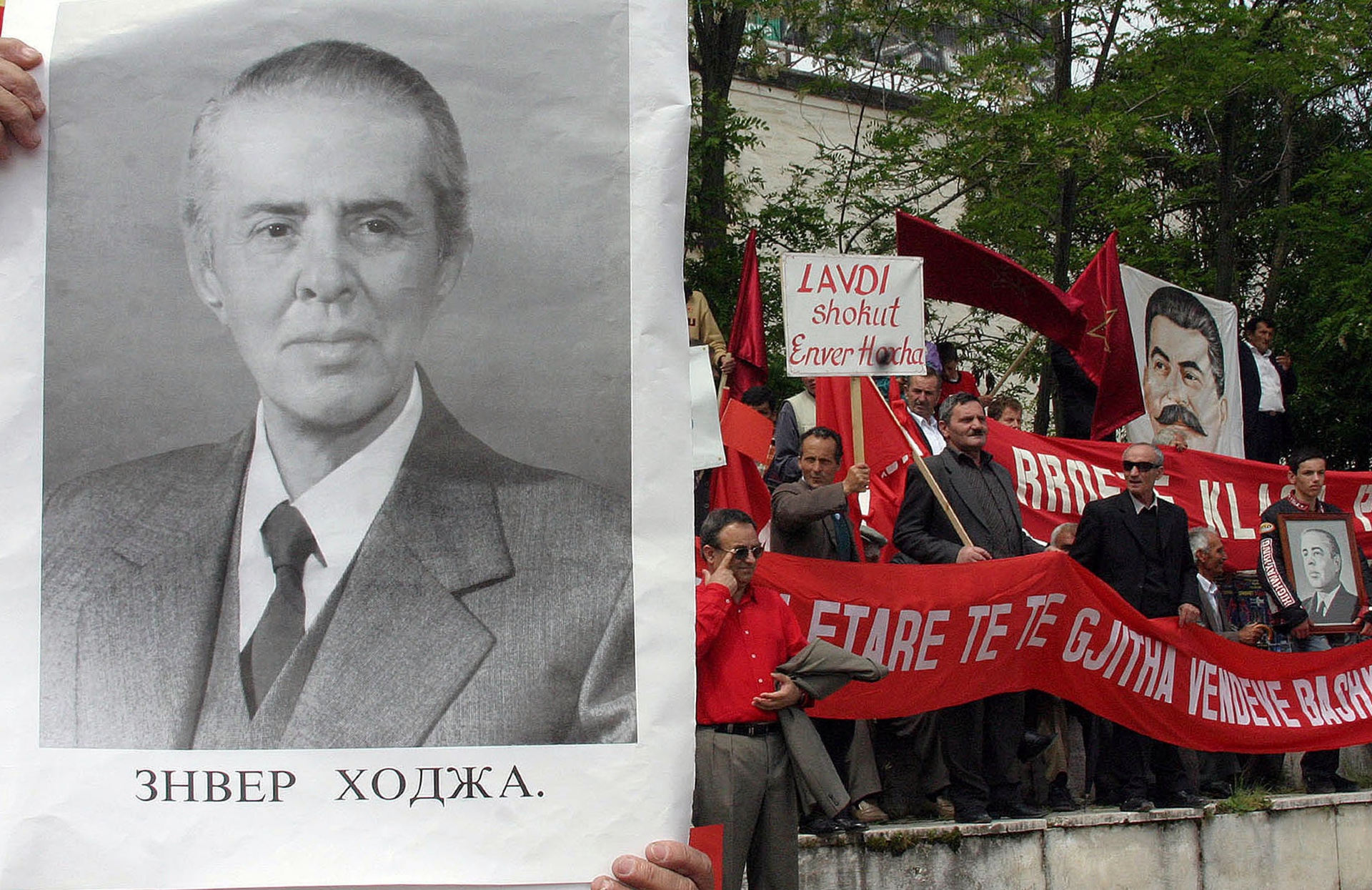 A supporter of Enver Hoxha carries his photo as other supporters shout slogans during May Day in Tirana in 2006