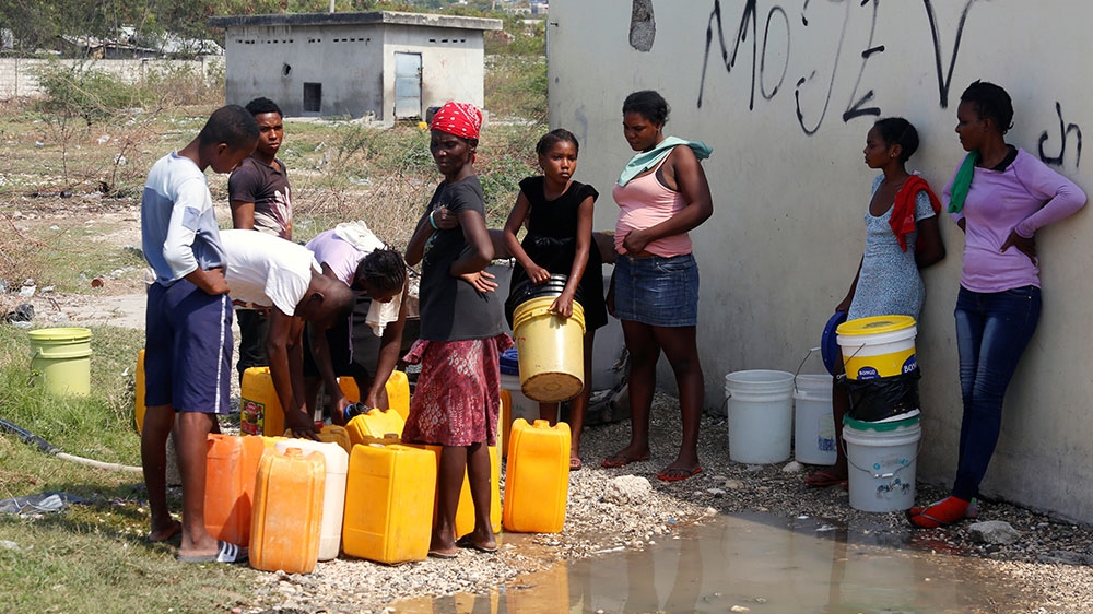 People wait to get water from a communal tap, during an outbreak of the coronavirus disease (COVID-19), in Port-au-Prince, Haiti
