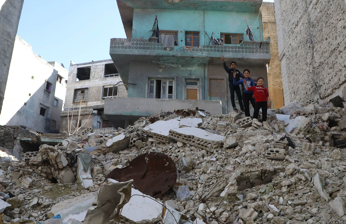 Children stand atop the debris of a building, destroyed by pro-regime forces air strikes, in the town of Ariha in the southern countryside of the Idlib province on April 11, 2020. - Several weeks into