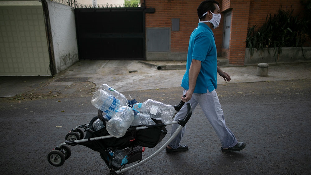 A man wearing a face mask amid the spread of the new coronavirus pulls a baby stroller filled with empty containers, as he walks to a mountainside to collect water in Caracas, Venezuela