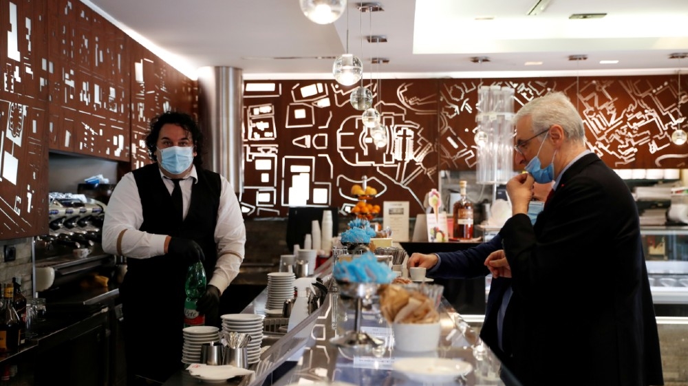 A man wearing a face mask serves a customer, as shops are allowed to reopen as Italy eases some of the lockdown measures put in place during the coronavirus disease (COVID-19)