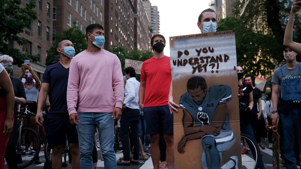 A man holds a drawing of former NFL player Colin Kaepernick as hundreds of people participate in a silent demonstration in New York City