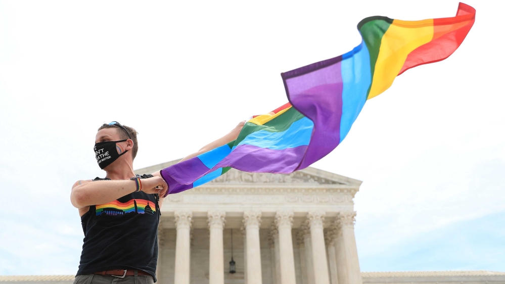 Joseph Fons holding a Pride Flag, standing in front of the US Supreme Court building in Washington, DC after the court ruled that a federal law banning workplace discrimination also covers sexual orientation