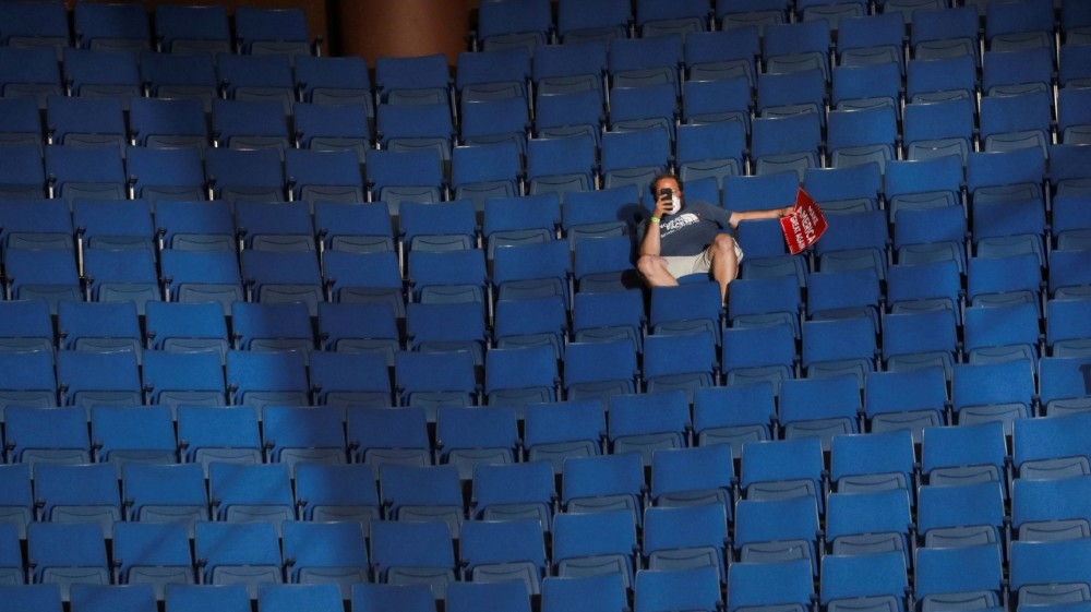 FILE PHOTO: A supporter of U.S. President Donald Trump shoots a video with his mobile phone from the sparsely filled upper decks of the arena as the president addresses