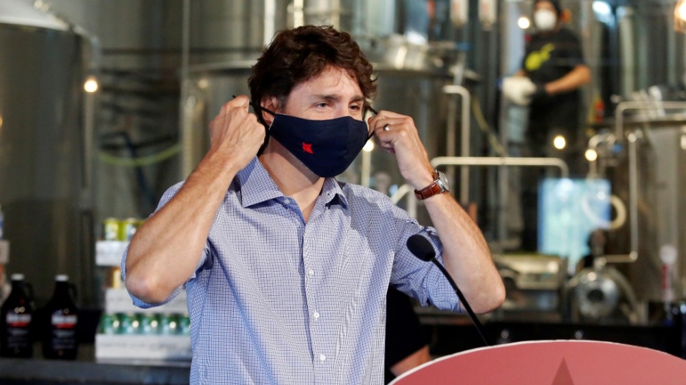 FILE PHOTO: Canada's Prime Minister Justin Trudeau removes his face mask as he visits the Big Rig Brewery, which utilizes the Canada Emergency Wage Subsidy given to businesses affected