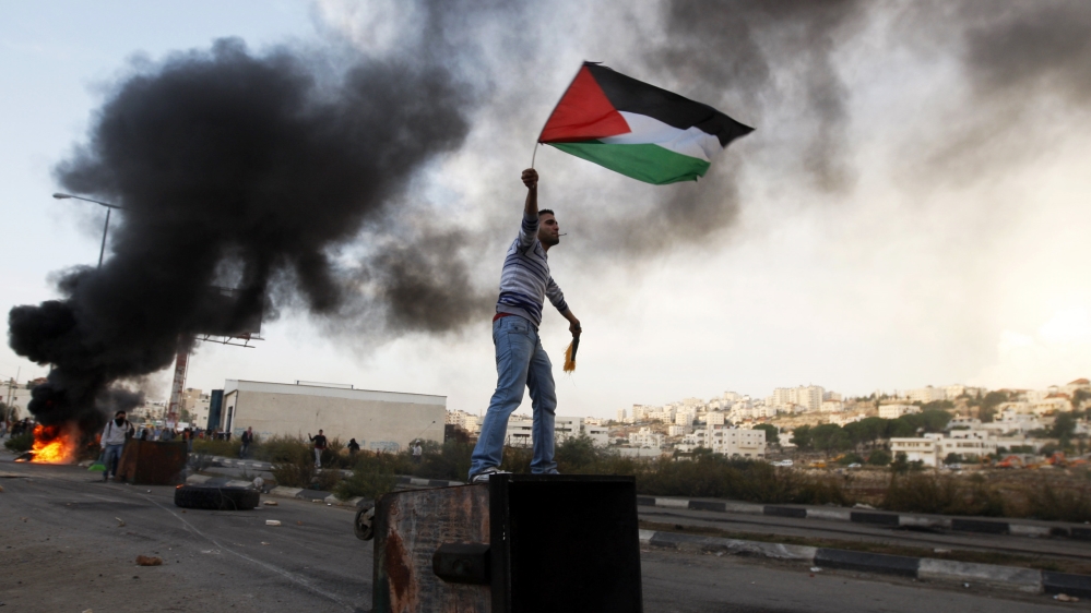 A Palestinian waves a national flag during a protest against Israel’s operations in the Gaza Strip