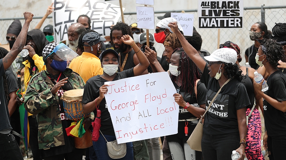 Protesters hold posters outside the US embassy in Kingston, Jamaica