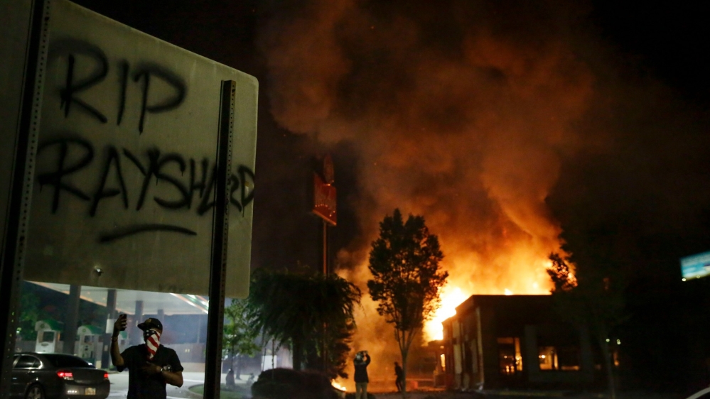 ‘RIP Rayshard’ is spray-painted on a sign as as flames engulf a Wendy’s restaurant during protests in Atlanta, Georgia. The restaurant was where Rayshard Brooks was shot and killed by police following a struggle in the restaurant’s drive-thru line