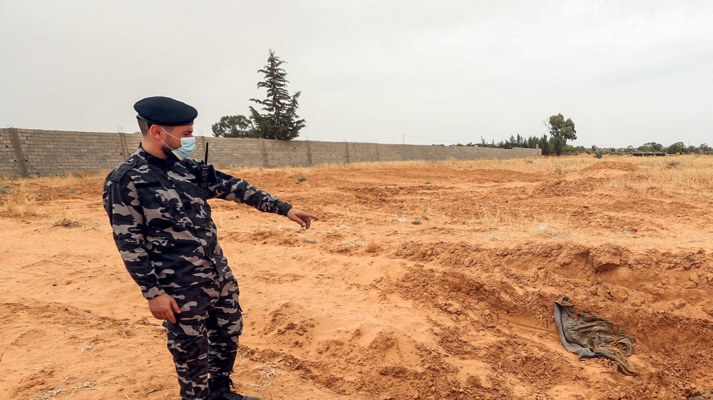 A member of security forces affiliated with the Libyan Government of National Accord (GNA)''s Interior Ministry points at the reported site of a mass grave in the town of Tarhuna, about 65 kilometres s