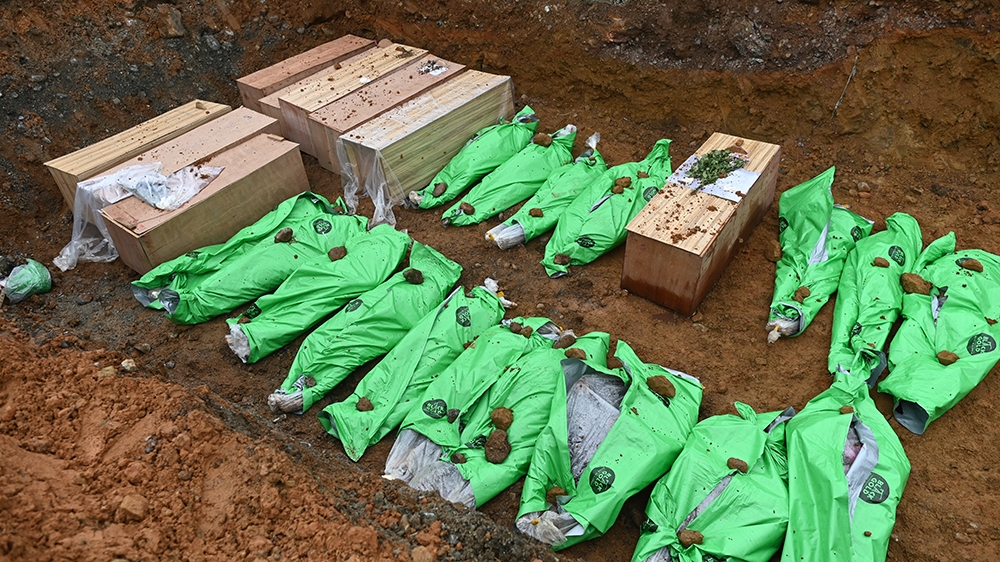 The bodies of miners in wooden coffins and wrapped up in bags pictured in a mass grave before being buried
