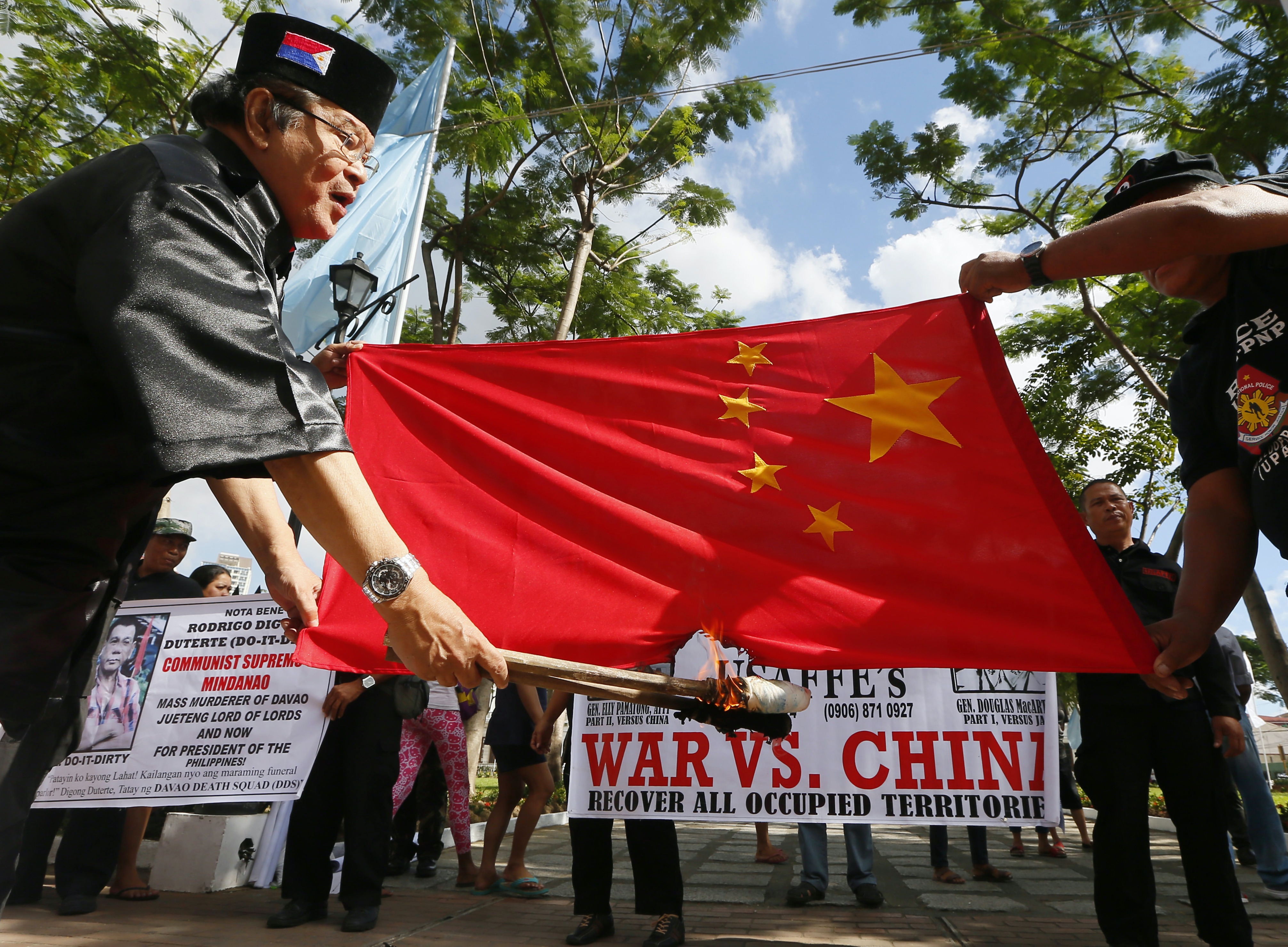 Philippine presidential candidate Elly Pamatong burns a Chinese flag in Manila on December 4, 2015, to denounce China’s island-building at the disputed Spratly Islands in the South China Sea