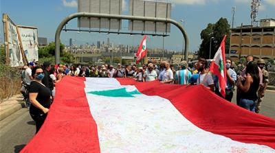 Demonstrators hold a makeshift Lebanese flag during a protest against government performance and worsening economic conditions near the presidential palace in Baabda, Lebanon