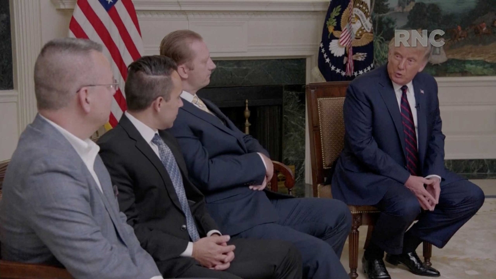 US President Donald Trump, flanked by people who were held hostage, speaking by video feed during the 2020 Republican National Convention broadcast from Washington, DC