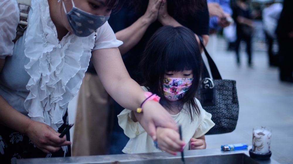 Visitors burn incense to pay tribute to the atomic bomb victims in front of the cenotaph at the Hiroshima Peace Memorial Park