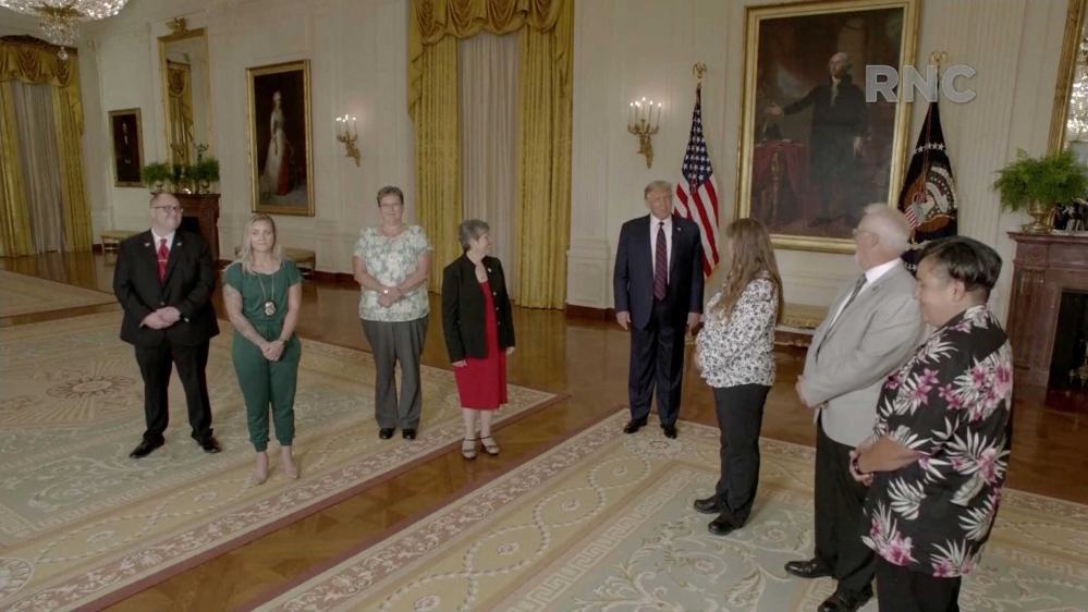 US President Donald Trump standing with essential workers and speaking by video feed during the Republican National Convention broadcast from Washington, DC