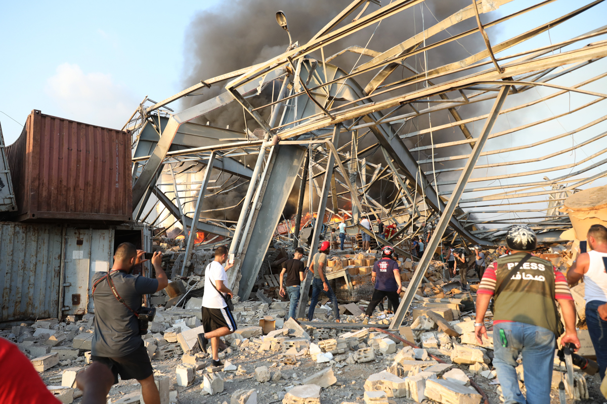 People walk at scene of an explosion in Beirut on August 4, 2020. - A large explosion rocked the Lebanese capital Beirut today, an AFP correspondent said. The blast, which rattled entire buildings and