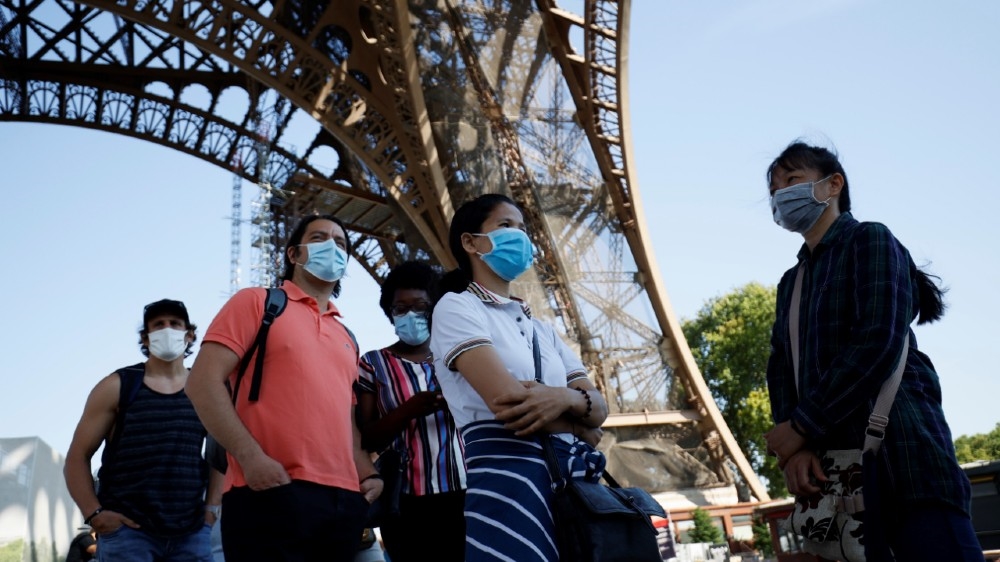 Visitors wearing protective facemasks queue as they wait for the partial reopening of Eiffel Tower on June 25, 2020, in Paris, as France eases lockdown measures taken to curb the spread