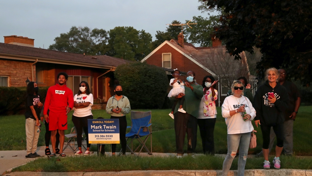 People in the neighbourhood try to catch a glimpse of the Democratic US presidential nominee and former Vice President, Joe Biden, as he a meets steelworkers at a back yard during his visit to Detroit, Michigan